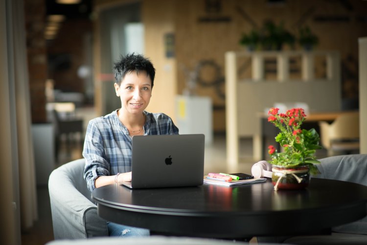 Kobieta siedzi przy stoliku z laptopem i przygotowuje się do szkolenia ze sprzedaży